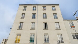 A multi-story building with a symmetrical facade, multiple windows with balconies, and a flat roof.