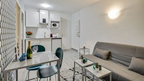A modern apartment with a dining area, kitchenette, and a living room with a sofa and coffee table.