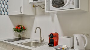 A modern kitchen with a built-in microwave, a sink with a faucet, a toaster, and a kettle.