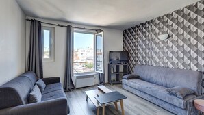 A modern living room with two grey sofas, a small table, and a TV stand. - 803 Suite Parisian - Superb apartment (Bagnolet)