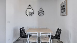A dining area with a wooden table and white chairs, two wall-mounted mirrors, and a framed quote on the wall. - 803 Suite Parisian - Superb apartment (Bagnolet)