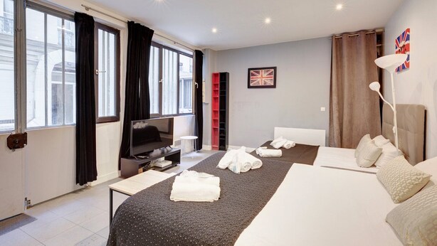 Een moderne hotelkamer met een groot bed, een televisie, een klein tafeltje en een raam met gordijnen.