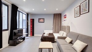 Een moderne woonkamer met een bank, een salontafel, een televisie en een rode boekenkast.