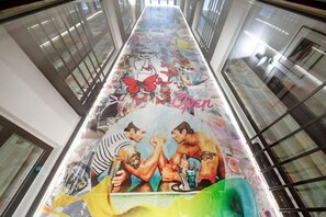 Vibrant mural adorns the hallway, featuring two figures in a lively handshake scene.