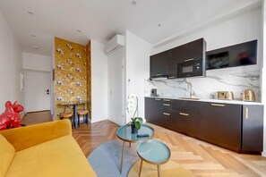 A modern kitchen with dark cabinets, a marble countertop, and a built-in microwave. - 210 Suite Chanel - Superb apartment in Paris (Paris 04 Hôtel-de-Ville)