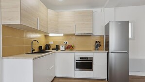 A modern kitchen with white cabinets, a stainless steel refrigerator, a built-in oven, and a sink. - 865 Suite Jasmin - Superb apartment (Montreuil)