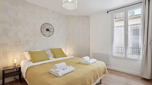 A hotel room with a bed, a bedside table, a wall clock, and a window with curtains. - 865 Suite Jasmin - Superb apartment (Montreuil)