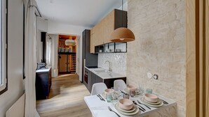 A modern kitchen with a stone backsplash, a dining area with a table set for four, and a walk-in closet with a mirror and hanging clothes. - 194 Suite Parisian house (Paris)
