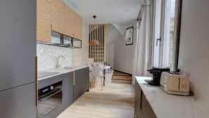 A modern kitchen with a large island, a dining area with a table and chairs, and a window with curtains. - 194 Suite Parisian house (Paris)