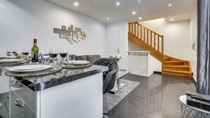 Une cuisine moderne avec un coin repas, un escalier et un salon.