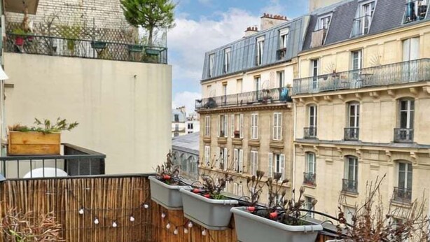 A balcony with a table set for breakfast, including croissants, orange juice, and wine glasses. - 675 Suite Bolivar - Superb apartment in Paris (Paris 19 Buttes-Chaumont)