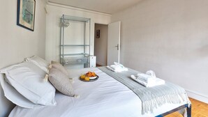 A hotel room with a bed, a side table with breakfast, a bathroom with a shower, and a door leading to another room. - 675 Suite Bolivar - Superb apartment in Paris (Paris 19 Buttes-Chaumont)