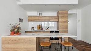 A modern kitchen with a marble countertop, wooden cabinets, and bar stools. - 620 Suite Martel - Superb apartment in Paris. (Paris 10 Entrepôt)
