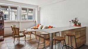 A modern kitchen with a large island, bar stools, and a view of the city through large windows. - 620 Suite Martel - Superb apartment in Paris. (Paris 10 Entrepôt)