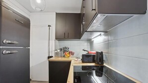 A modern kitchen with a black refrigerator, a built-in oven, and a microwave on a wooden countertop. - 867-Suite Mimosa - Superb Apartment (Montreuil)