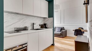A modern kitchen with white cabinets, a marble countertop, and a built-in oven. - 240 Suite Elysée - Superb apartment in Paris (Paris 08 Élysée)