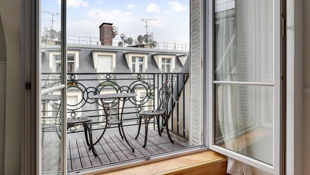 A balcony with a view of neighboring buildings, a small table, and two chairs. - 240 Suite Elysée - Superb apartment in Paris (Paris 08 Élysée)