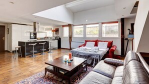 A modern hotel room with a large bed, a sofa, a dining area, and a kitchen. - 2•5•9 Suite Suzy • Cosy Duplex • Paris (Paris 11 Popincourt)
