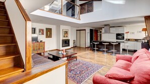 A spacious living area with a high ceiling, a staircase, a kitchen, and a dining area. - 2•5•9 Suite Suzy • Cosy Duplex • Paris (Paris 11 Popincourt)