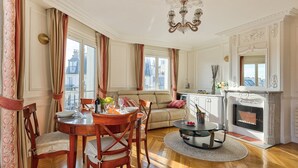A spacious living room with a dining area, a fireplace, and a view of the city.