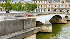 Eine Steinbrücke über einem Fluss, im Hintergrund ein historisches Gebäude.