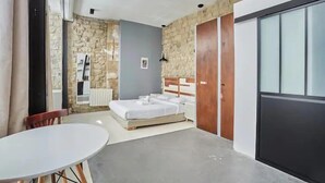 A bedroom with a bed, a table, and a wardrobe. - 294 Suite Naza - Superb apartment in Paris (Paris 03 Temple)