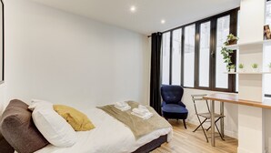 A modern bedroom with a bed, a desk, and a chair. - 318 Suite Pivert - Superb apartment in Paris (Paris 11 Popincourt)