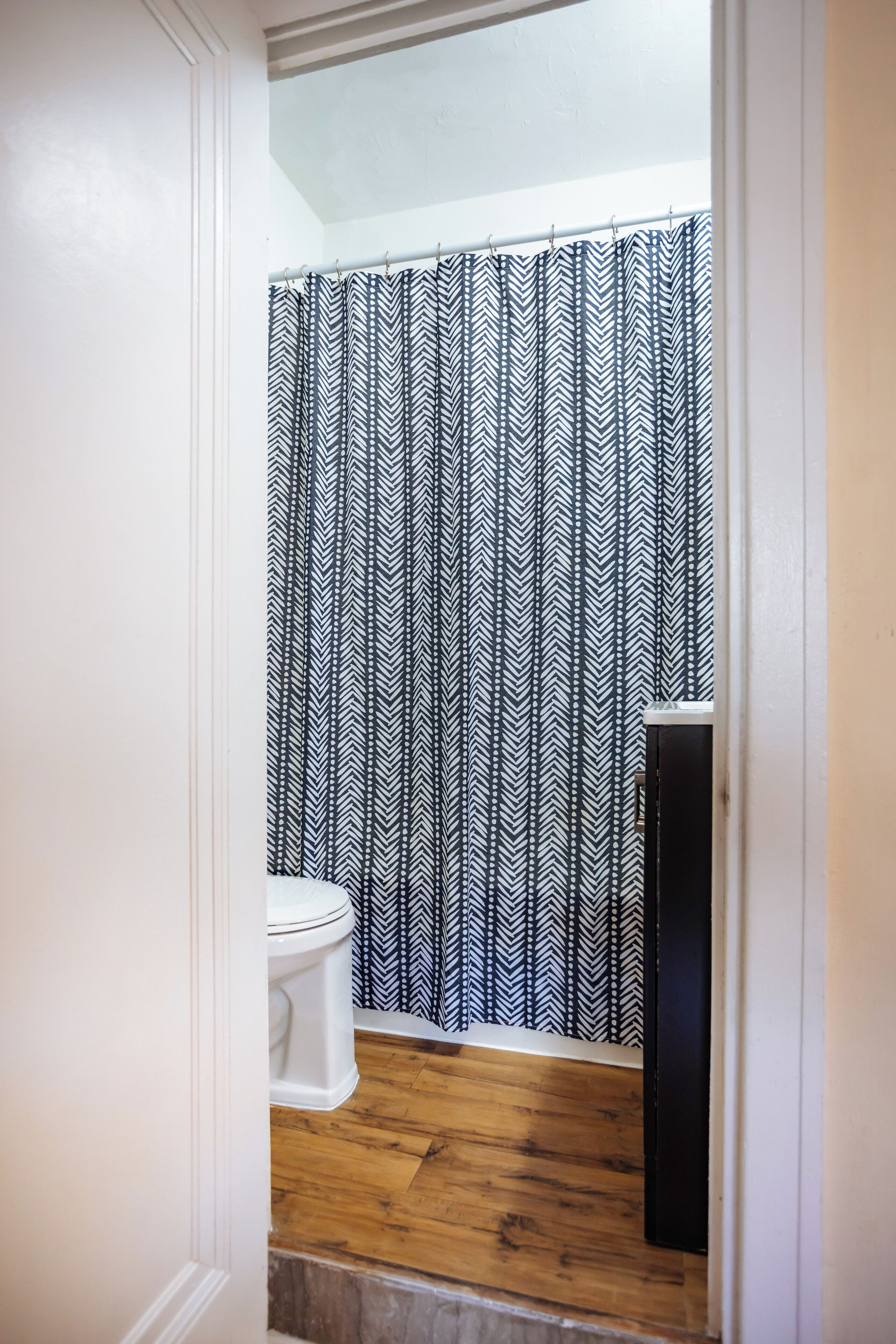 Une salle de bain avec des toilettes blanches, un plancher en bois et un meuble noir.