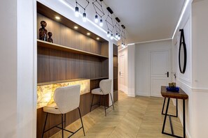 Enter a stylish hallway leading to a room with a wooden floor, featuring two chairs and a small table.