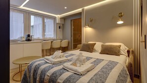 A modern hotel room with a bed, bedside tables, a desk with chairs, a window, and a bathroom. - 369 Suite Fondary 5 - Superb apartment in Paris (Paris 15 Vaugirard)