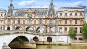 Un edificio histórico con un puente sobre un río, que presenta arquitectura clásica y múltiples arcos.