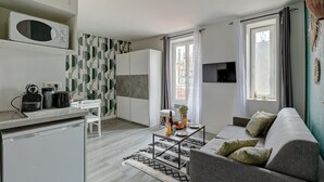 Ein modernes Apartment mit Küche, Essbereich und Wohnzimmer. Es verfügt über einen Flachbildfernseher, eine Couch und einen Couchtisch.