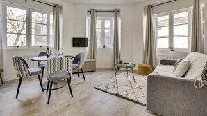 A modern living room with a dining area, large windows, a flat-screen TV, and a cozy sofa. - 151 Suite Jean Yves - Superb Studio in Paris (Paris 13 Gobelins)