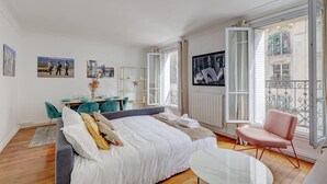 A bedroom with a bed, a desk, and a chair. There are windows and a balcony. - 629 Suite Damremont - Superb apartment in Paris (Paris 18 Buttes-Montmartre)