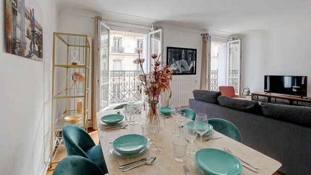 A modern living room with a dining area, a grey sofa, and a TV. - 629 Suite Damremont - Superb apartment in Paris (Paris 18 Buttes-Montmartre)