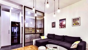A modern living room with a dark sofa, glass coffee table, and a wooden floor. - 113 Suite Lui - Sumptuous apartment in Paris (Paris)