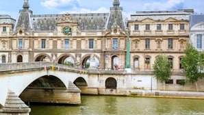 Ein historisches Gebäude mit einer Brücke über einem Fluss, mit klassischer Architektur und einem Uhrturm.