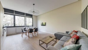 Ett modernt vardagsrum med en grå soffa, ett soffbord och en matplats med ett bord och stolar.