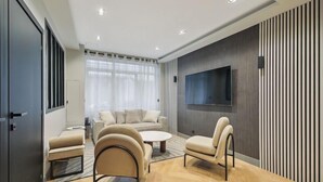 A modern living room with a sofa set, two armchairs, a coffee table, and a flat-screen TV mounted on the wall. - 327 Suite Le Marais - Superb apartment in Paris (Paris 03 Temple)
