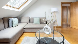 A modern living room with a sectional sofa, a glass coffee table, a white vase with branches, and a floor lamp. - The Acton Collect (London)