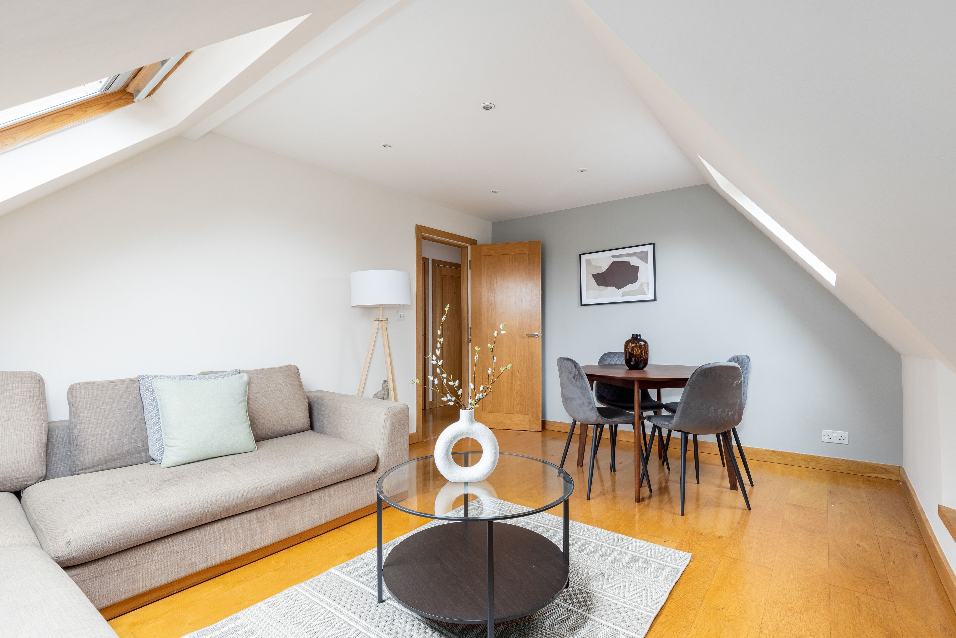 Un salon moderne comprenant un canapé, une table basse en verre et un coin repas avec des chaises et une table.