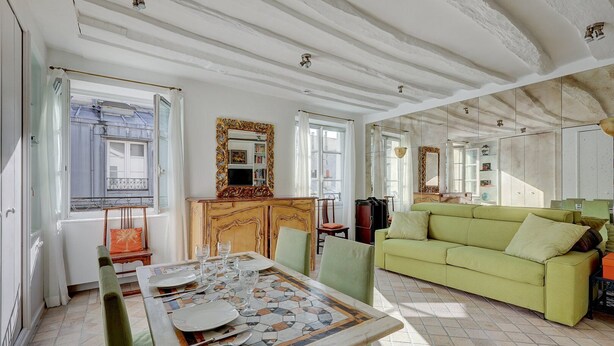 A dining area with a mosaic table, a green sofa, and a mirrored wall. - 630 Suite Yoake - Superb apartment in Paris (Paris 01 Louvre)