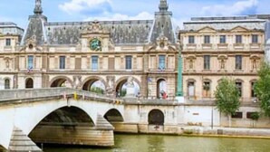 Un bâtiment historique avec un pont enjambant une rivière, caractérisé par une architecture classique et une tour horloge.