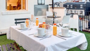 Ein Frühstückstisch auf einer Dachterrassen mit Blick auf die Stadt, inklusive Balkon und Essbereich mit Stühlen und Tischen.