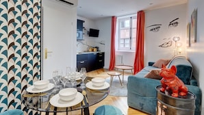 Een moderne woonkamer met een eethoek, een keuken op de achtergrond en een rode vosbeeldje op een metalen bak.