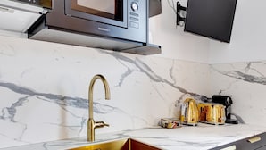 Een keuken met een gouden kraan, een magnetron en een broodrooster op het aanrecht.