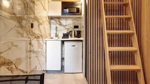 A compact kitchen with a built-in microwave, a sink, and a stove. There is a wooden ladder leading to a lofted sleeping area. - 366 Suite Legendre - Superb apartment in Paris (Paris 17 Batignolles-Monceau)