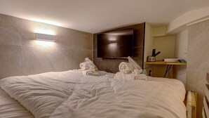 A hotel room with a bed, a flat-screen TV mounted on the wall, and a small shelf with a remote control and a charging station. - 366 Suite Legendre - Superb apartment in Paris (Paris 17 Batignolles-Monceau)