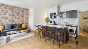 A modern kitchen with a central island, built-in appliances, and a seating area with a sofa and chairs. - 626 Suite Rambuteau - Superb apartment in Paris (Paris 04 Hôtel-de-Ville)