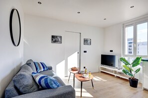 Relax in this stylish living room with a sofa, side table, flat-screen TV, and a potted plant.